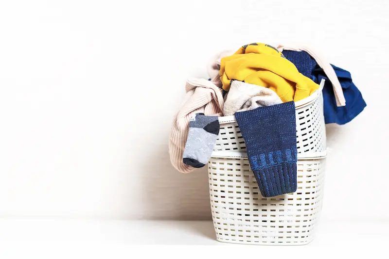 white laundry basket overflowing with dirty clothes