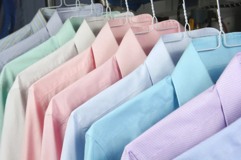 row of pastel men's shirts hanging at dry cleaners