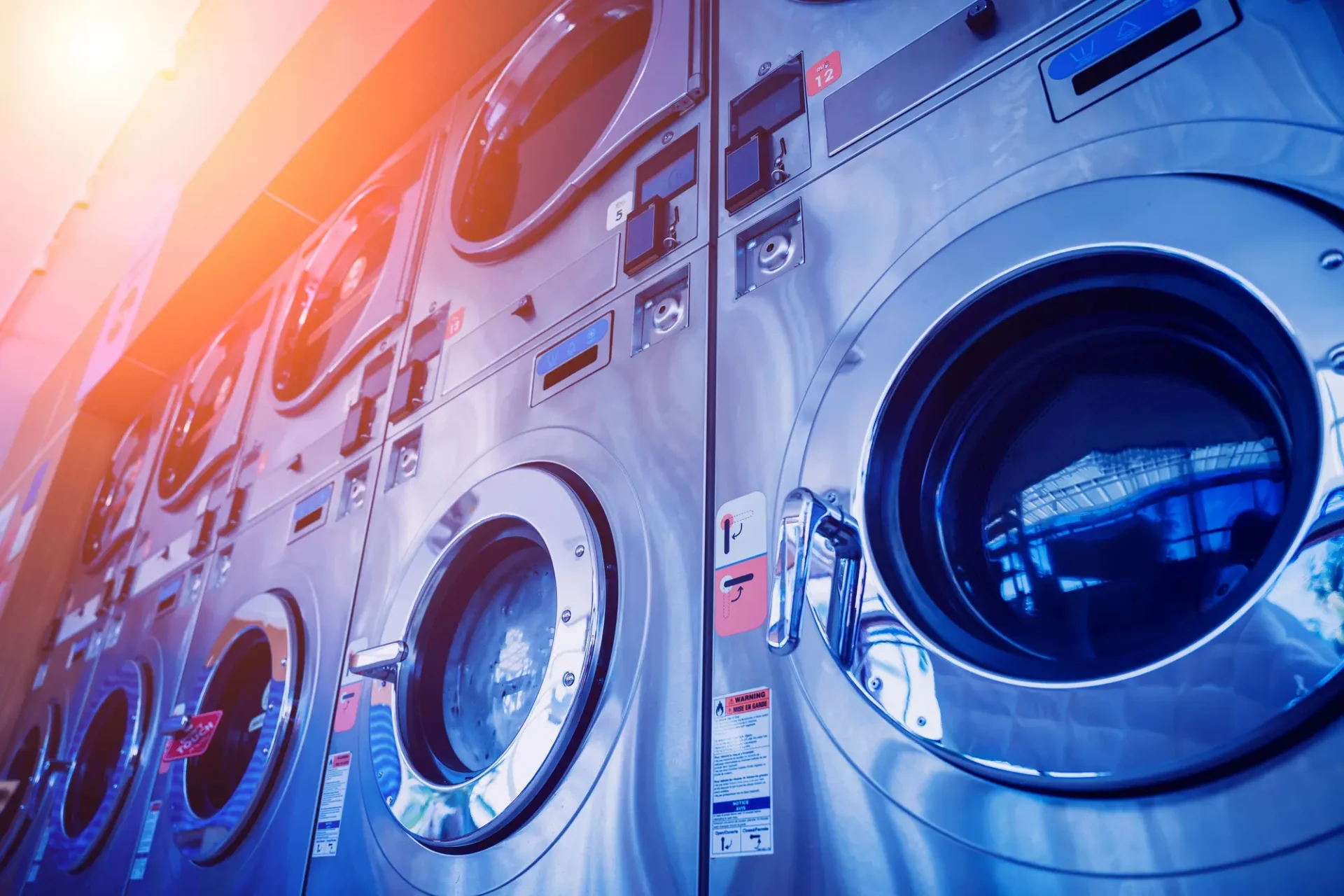 rows of industrial washing machines with sunlight in corner